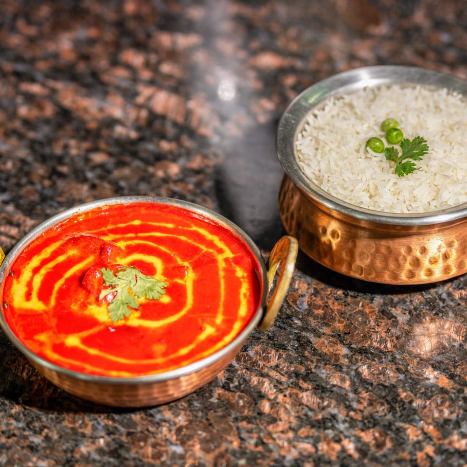 Jhapali Kitchen & Bar's chicken tikka masala and rice, served in traditional copper bowls.