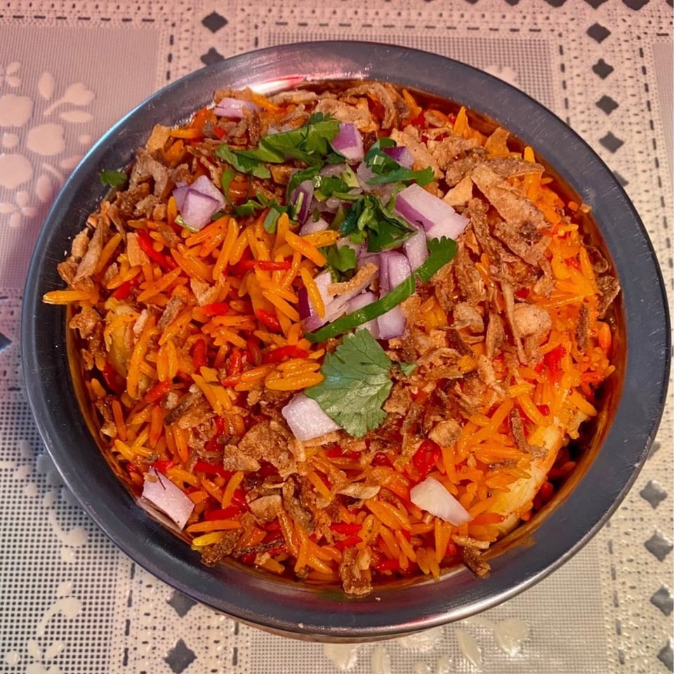 A close-up of Jhapali Kitchen & Bar's Nepalese rice dish with fried onions, red onions, and cilantro.