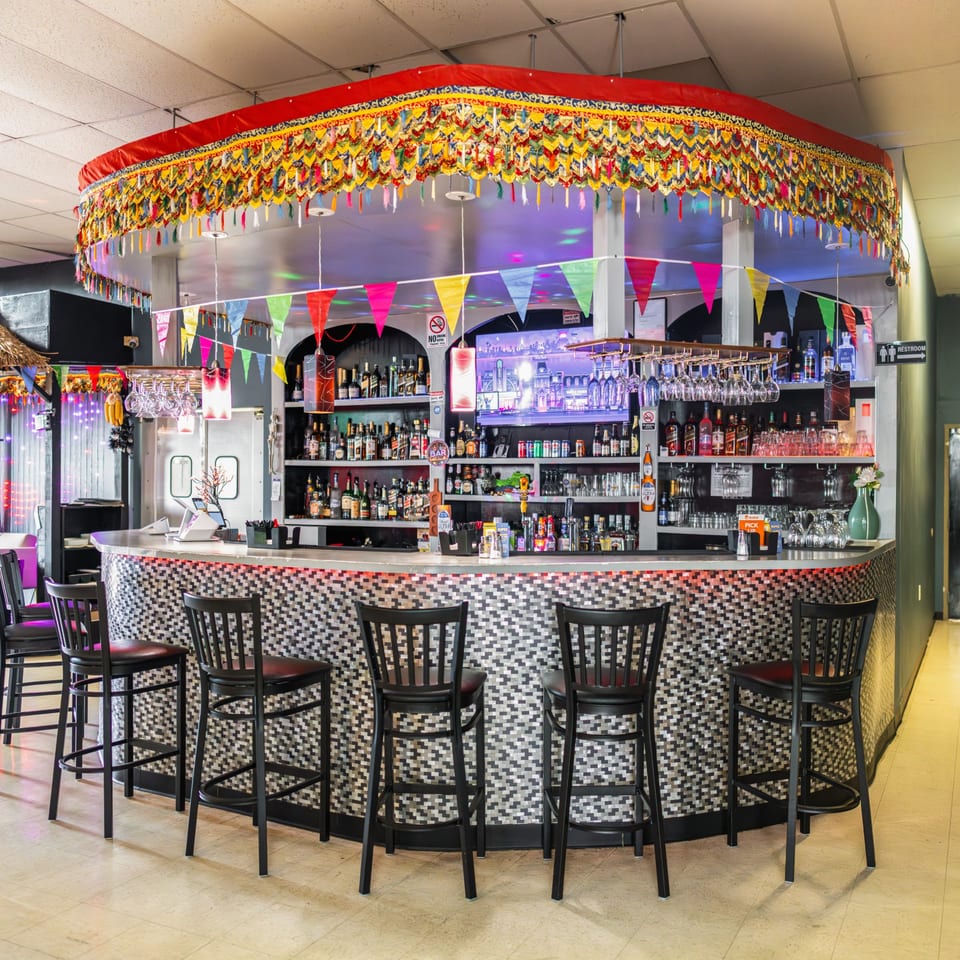 A vibrant, circular bar at Jhapali Kitchen & Bar, adorned with colorful Nepalese decorations and stools.