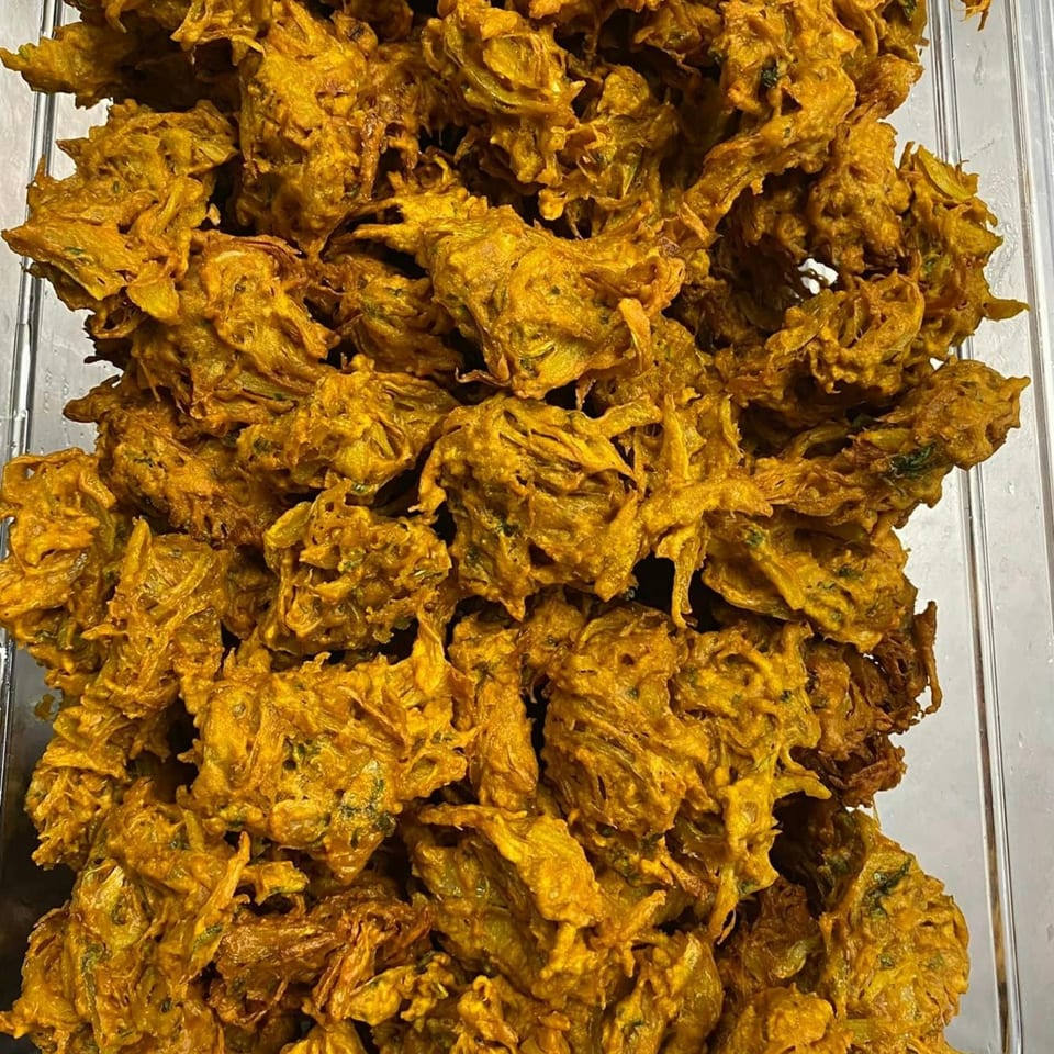 A close-up of golden-brown Nepalese vegetable pakora, crispy and irregularly shaped, filling the frame.